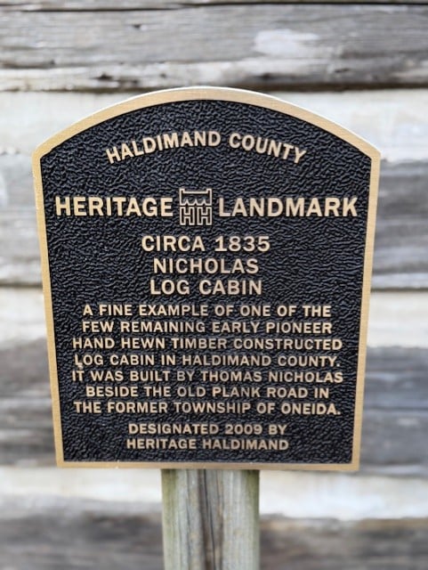 Haldimand County Heritage Landmark plaque for the circa 1835 Nicholas Log Cabin, a hand hewn timber pioneer cabin located at Courthouse Park in Cayuga, Ontario